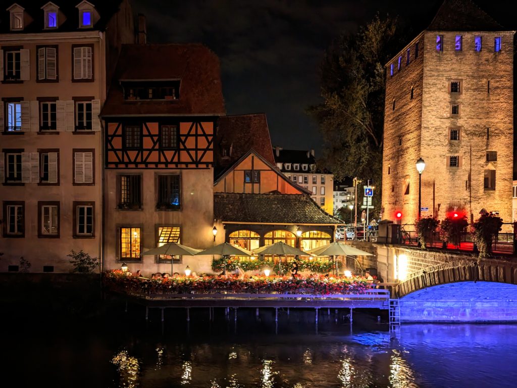 Covered Bridge in Strasbourg at nighttime and a restaurant with an outside terrace
